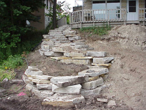The retaining walls above and below the steps had to be constructed at the same time as the winding lannon stone staircase was installed to meet the existing walkway.