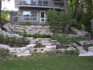 This photo was taken a couple months after the project was installed. The picture shows the careful attention that was given to the choice of the retaining wall stone used to work well with the site and with the existing stone of the house.