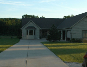 Before Construction: The existing driveway approach to the house is a sea of concrete abutting directly against the building wall. An existing Pine tree unfortunately blocks the visibility to the front door from the end of the driveway. The front yard landscape provides very little curb appeal. The proposed design addressed all these concerns.