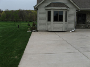Before Construction: The existing concrete driveway abuts up to the building foundation allowing no room for hard surface relief. The concrete also abuts the front porch creating no sense of warmth. The area is extremely uninviting, desolate and in need of improvement.