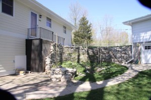 Before – The existing stoop was supported by an unattractive exposed concrete block wall and the slope was retained by an unorganized array of failing lannon stone retaining walls.